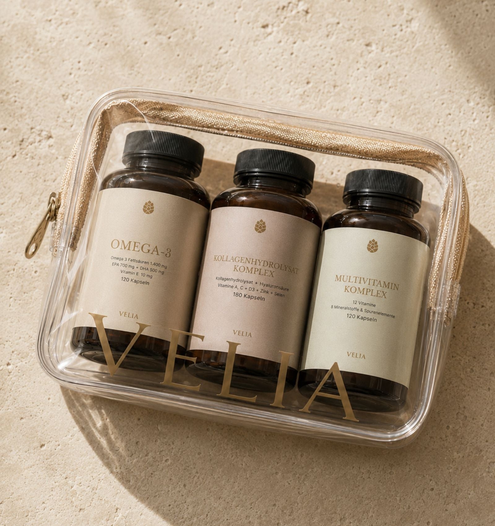 VELIA Omega-3, Kollagenhydrolysat Komplex und Multivitamin Komplex in einer transparenten Tasche auf hellem Kalksteinuntergrund